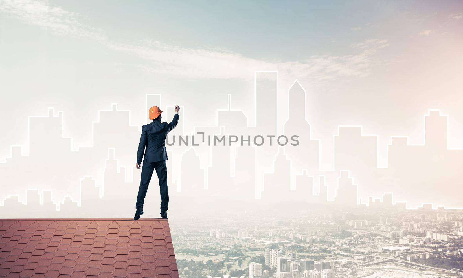 Engineer man standing with back on house roof and drawing city. Mixed media