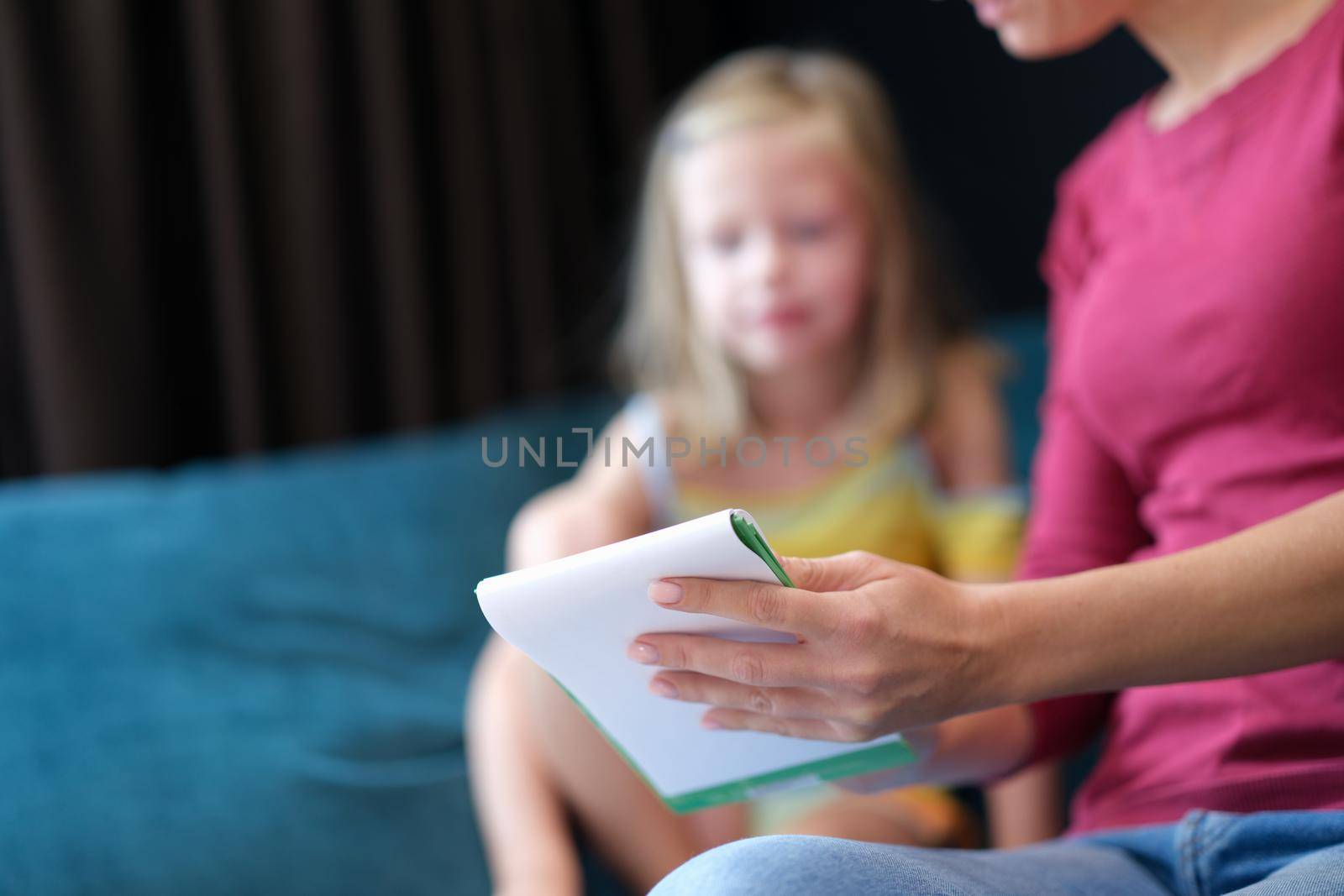 Mom shows learning notebook for daughter. Joint educational homework with children concept