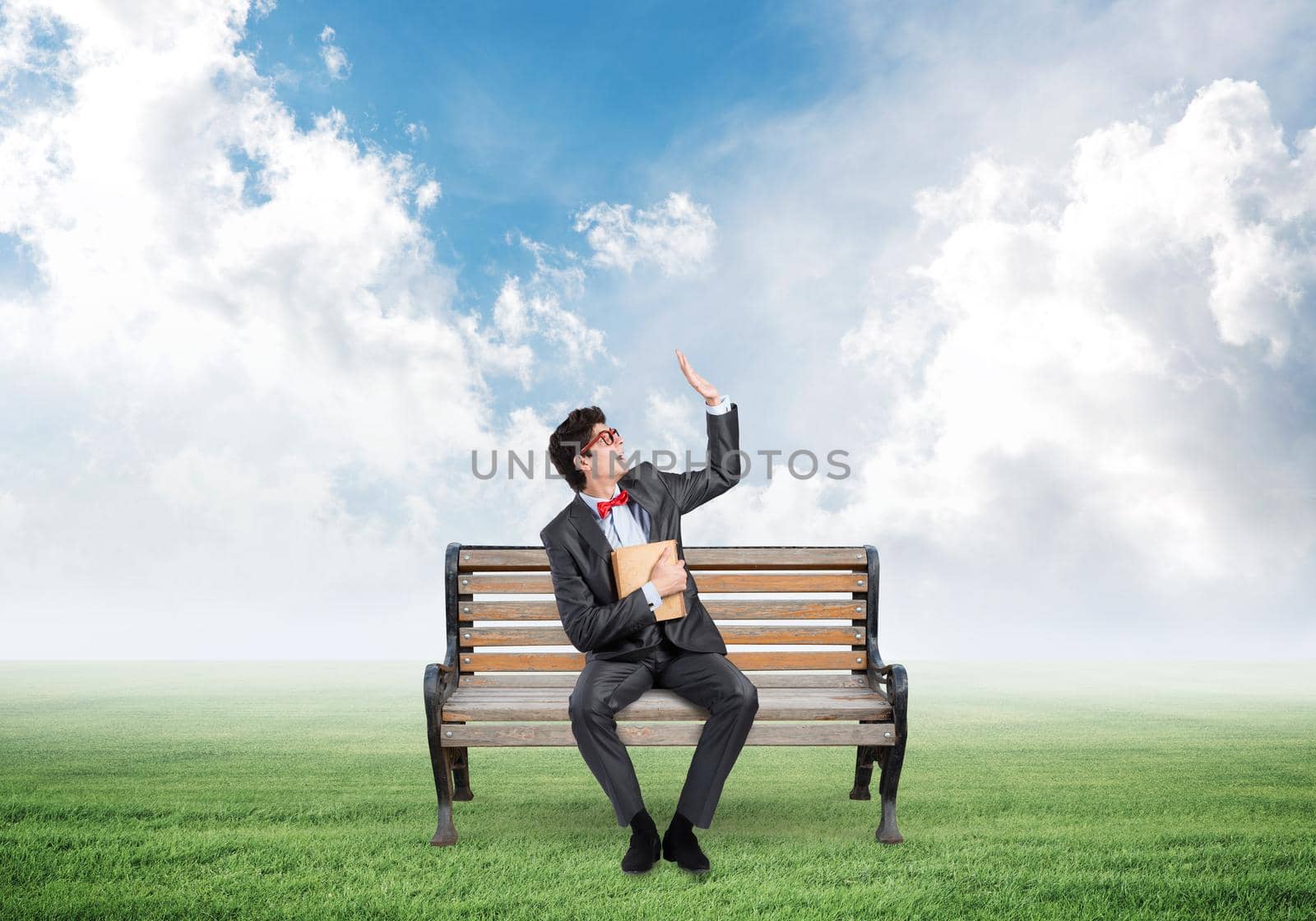 young student with a book. sits on a wooden bench
