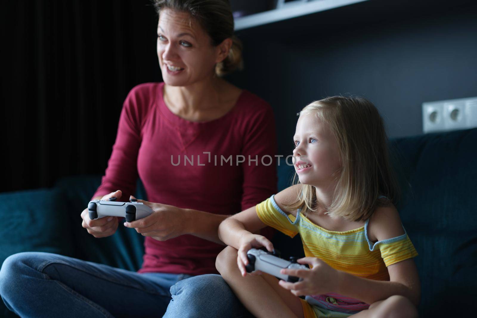 Mom and daughter hold game joysticks and play online games by kuprevich