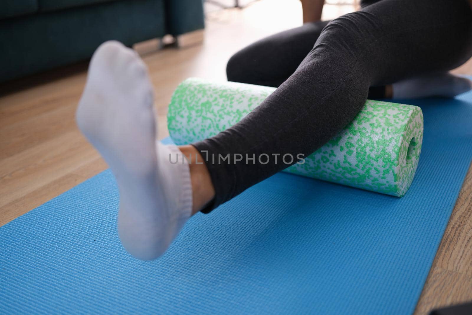 Woman massaging leg with foam roller closeup by kuprevich