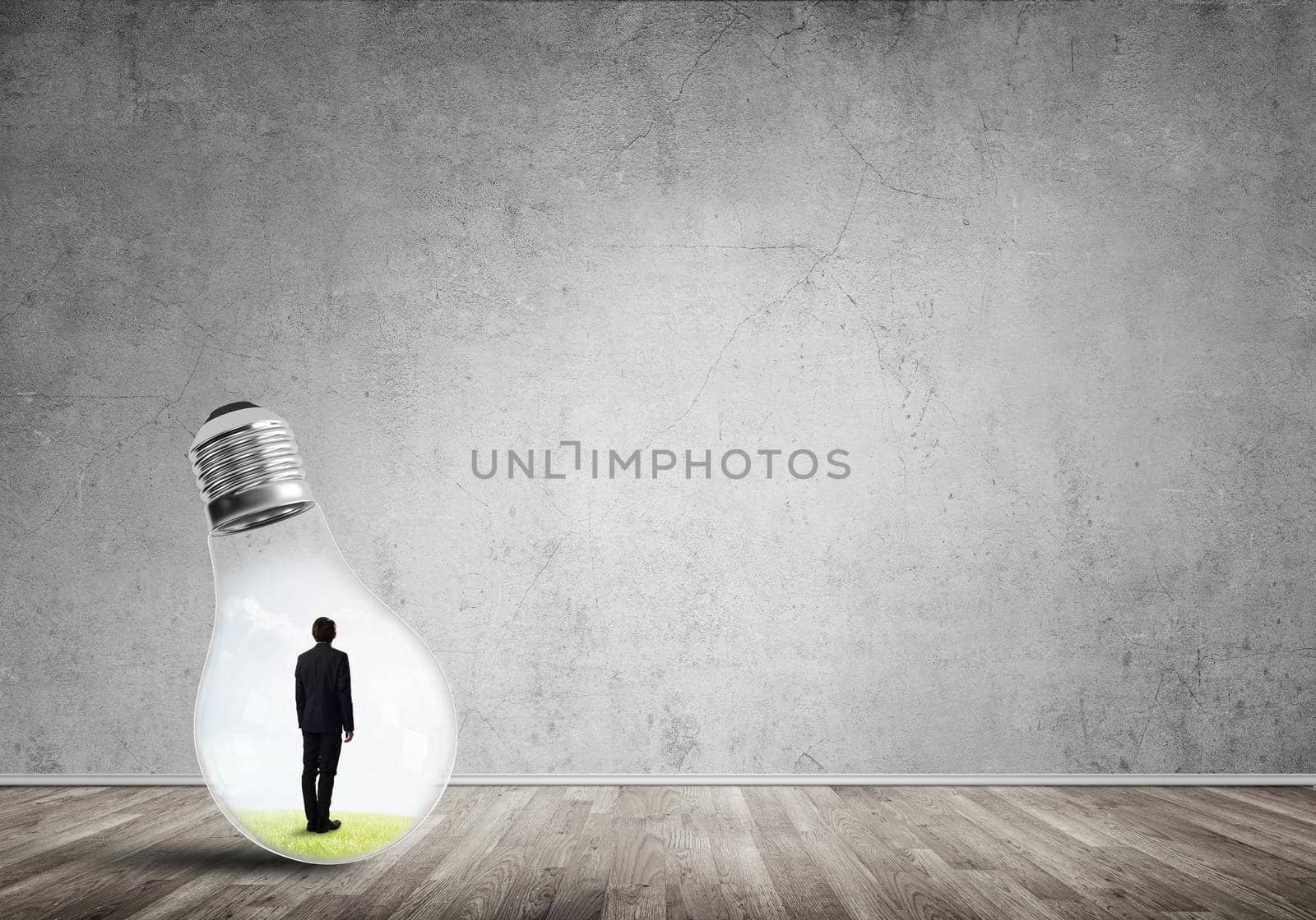 Businessman inside of light bulb in empty concrete room