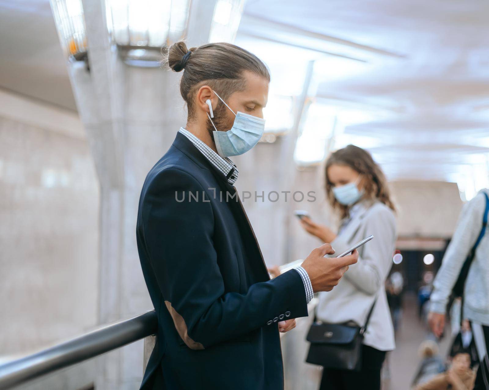 man and a woman in protective masks waiting for a train in the subway. by SmartPhotoLab