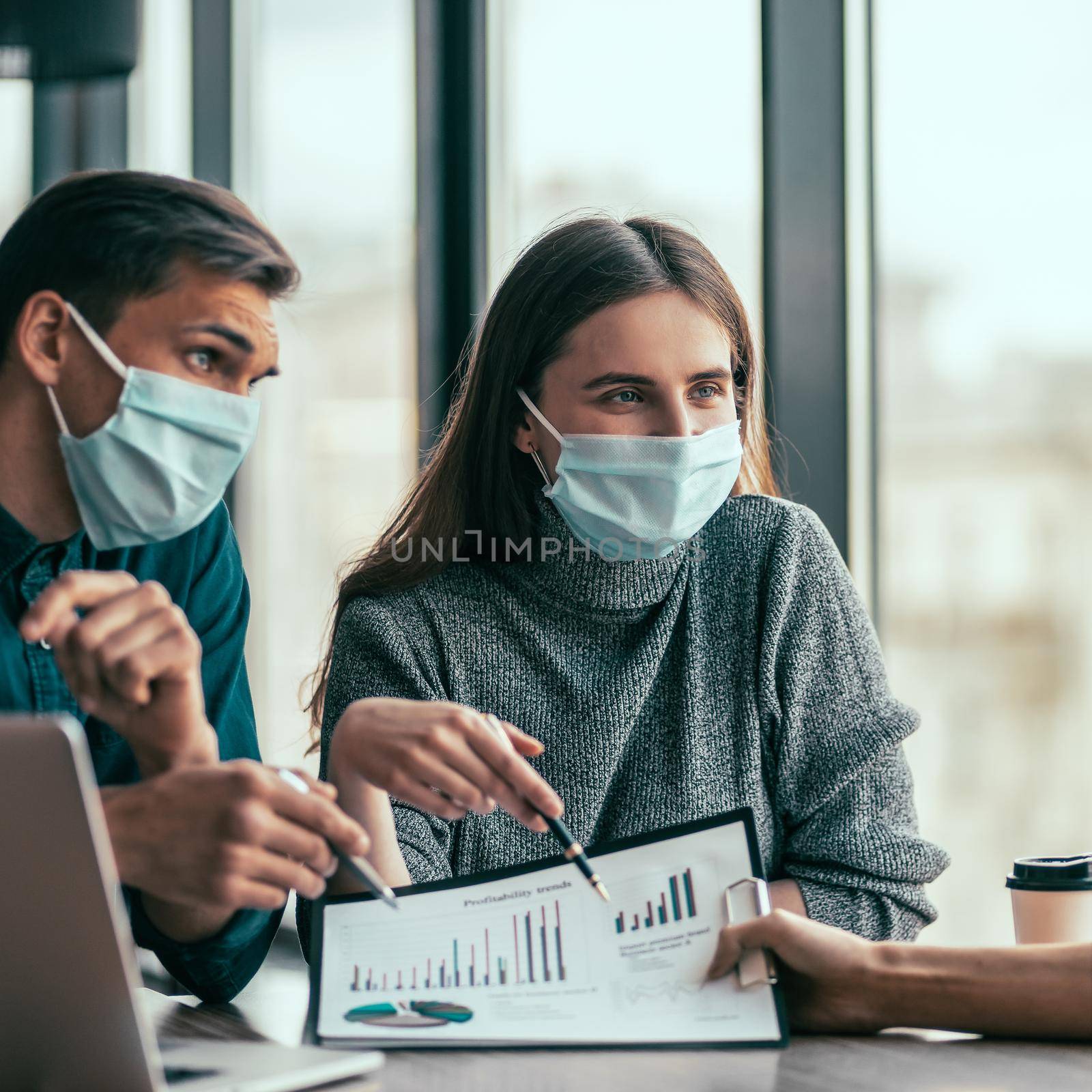 young woman in a protective mask talking to her colleague. by SmartPhotoLab