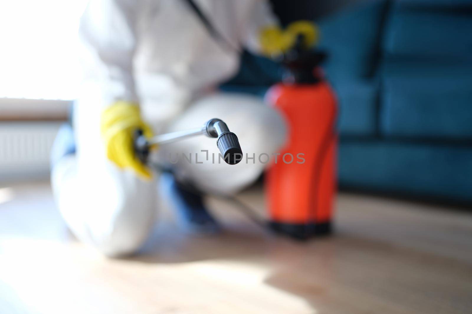 Prevention of spread of virus and rodents indoors. Disinfectant in protective suit and mask sprays disinfectants in home or office concept