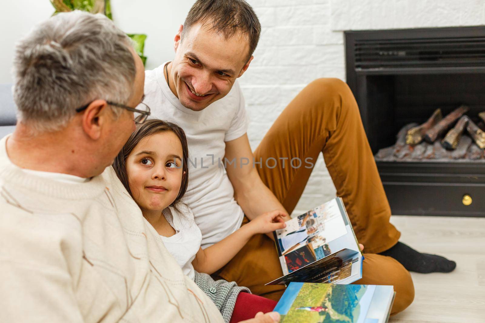 Smiling family with grandparents holding photo album at home.