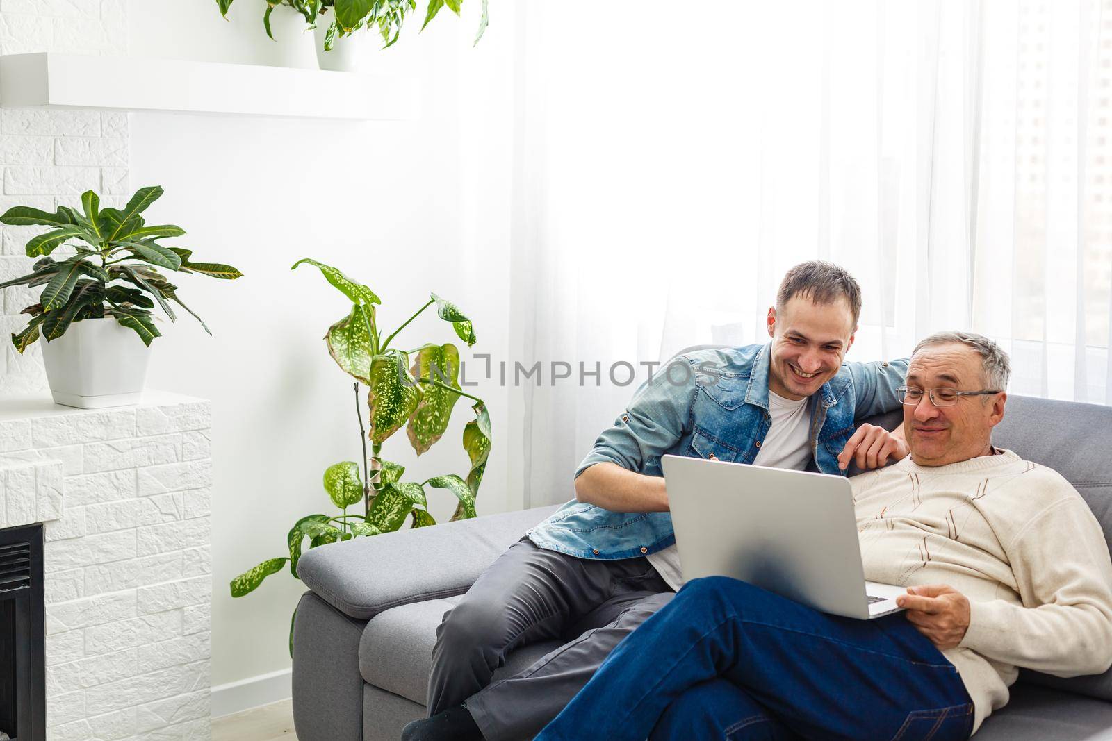 Senior man using laptop PC with his adult son