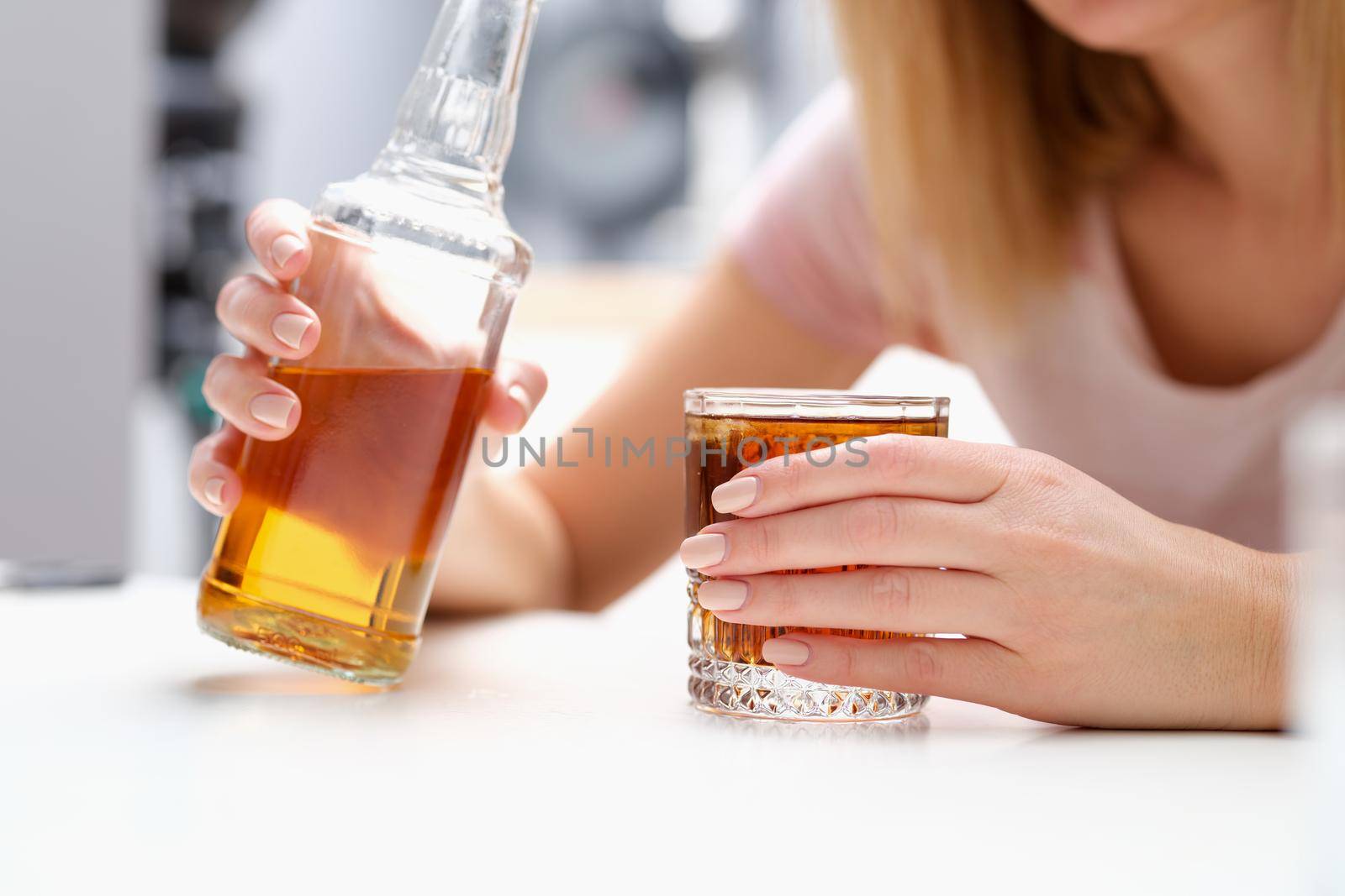 Woman with bottle of alcohol and glass alone. Depression and female alcoholism concept