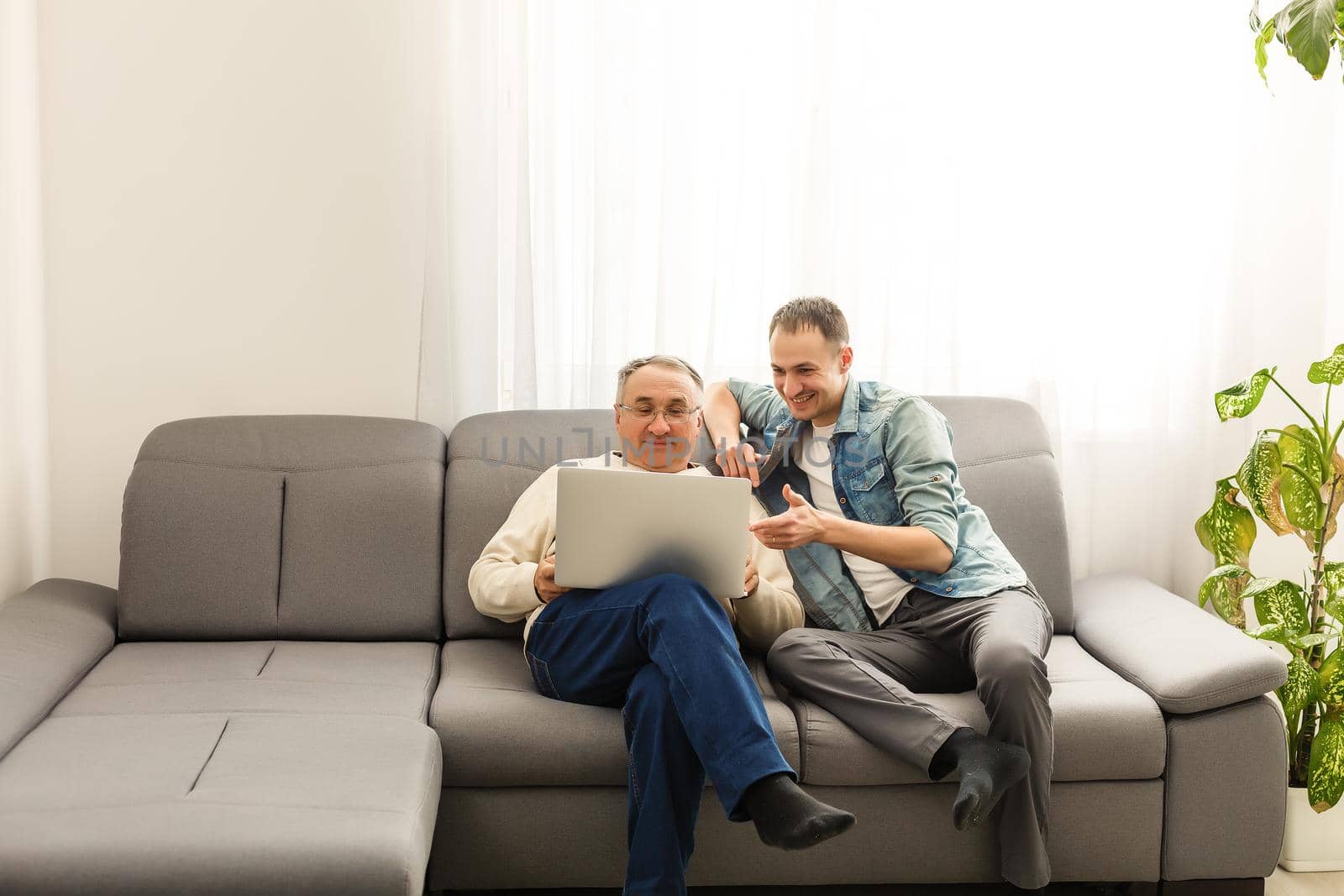 Old father and son are friendly conversation sitting at home on sofa