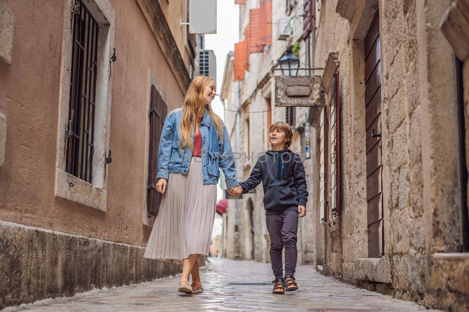 Mom and son travelers enjoying Colorful street in Old town of Kotor on a sunny day, Montenegro. Travel to Montenegro concept by galitskaya