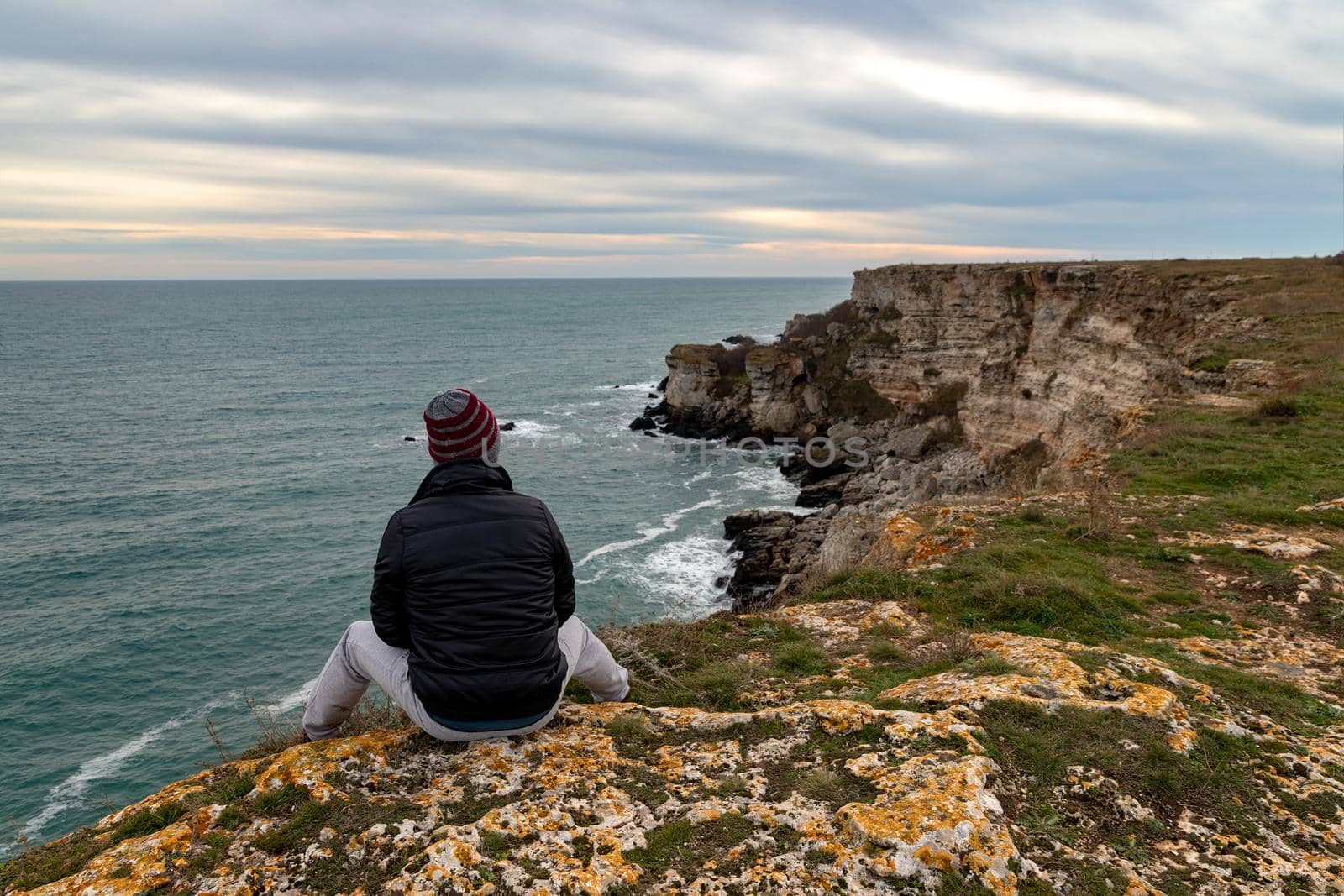 A man enjoys a beautiful sea view from the top of a cliff.