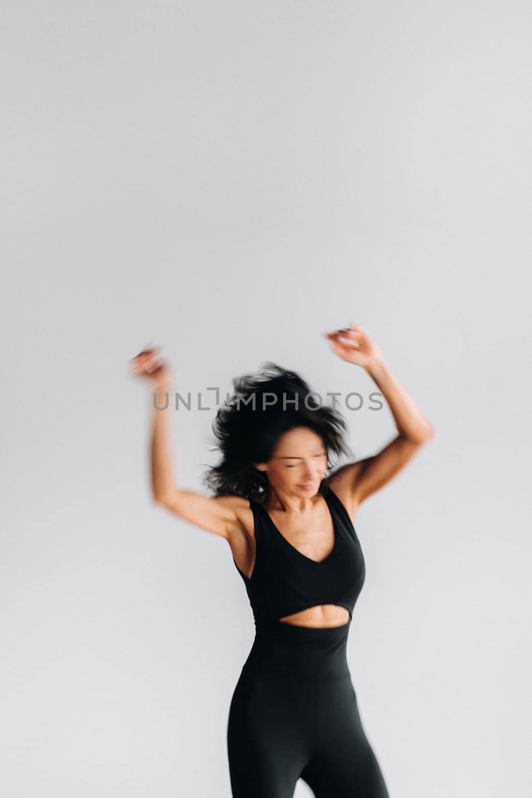 A blurry silhouette of a woman in black sportswear is engaged in dynamic kali meditation in the yoga hall by Lobachad