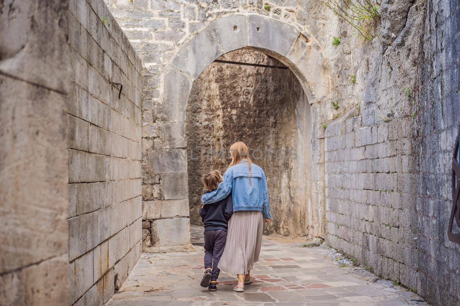 Mom and son travelers enjoying Colorful street in Old town of Kotor on a sunny day, Montenegro. Travel to Montenegro concept.