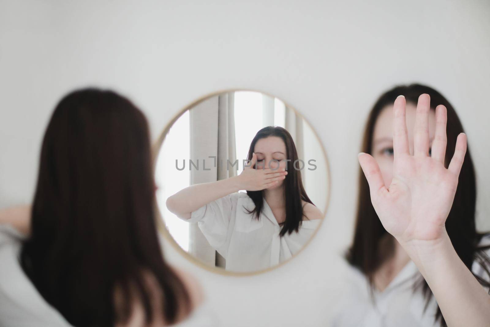 young woman looking in the mirror. Mental health problems in self-isolation at home. Reflection in mirror. Depression, anxiety, phobia, suicide and mental health concept.