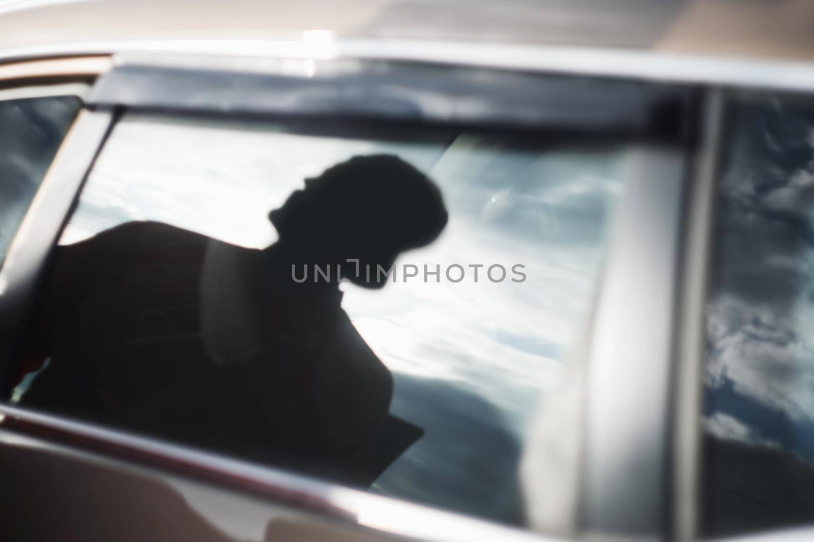 Man silhouette and sky with clouds reflected in the car window. Travel, adventure, road trip concept by paralisart