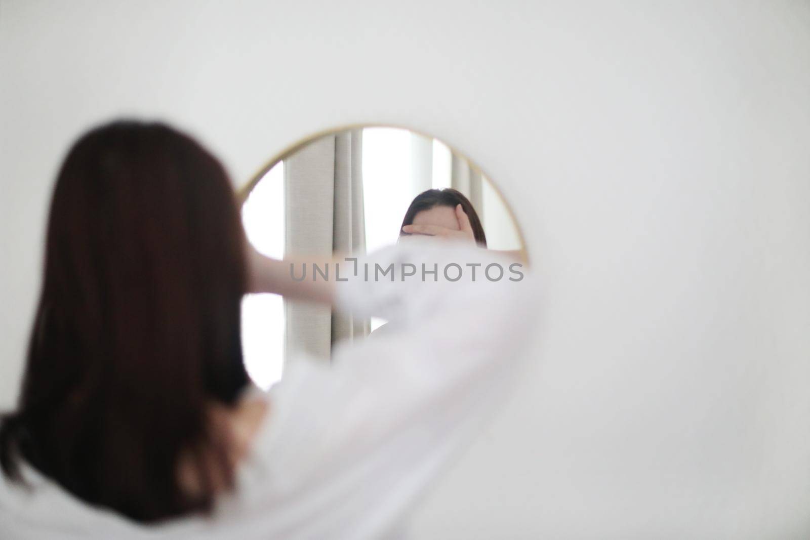 young woman looking in the mirror. Mental health problems in self-isolation at home. Reflection in mirror. Depression, anxiety, phobia, suicide and mental health concept.