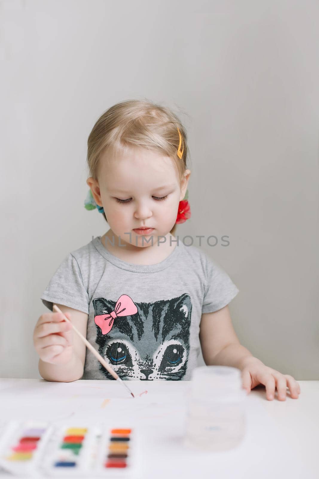 Child painting and drawing with watercolor paint at white table. Development of creative potential in children