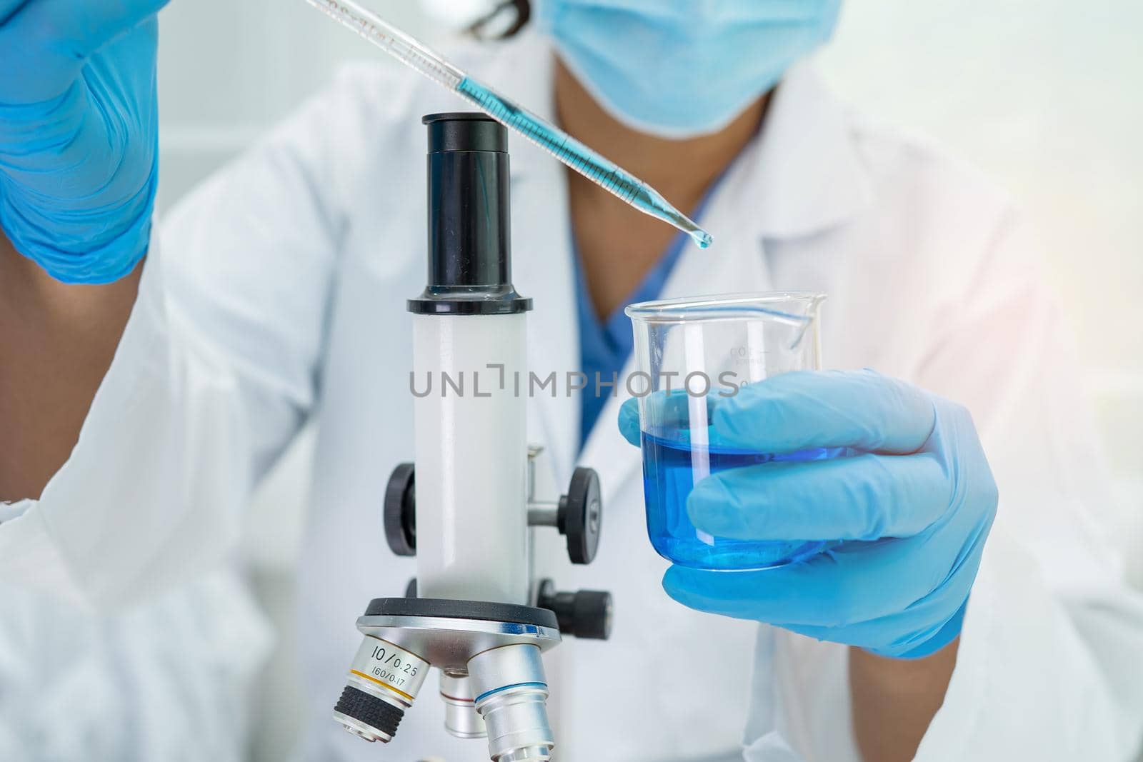 Asian scientist biochemist or microbiologist working research with a microscope in laboratory. For protect outbreak Coronavirus Covid19, bacteria and germs. by pamai