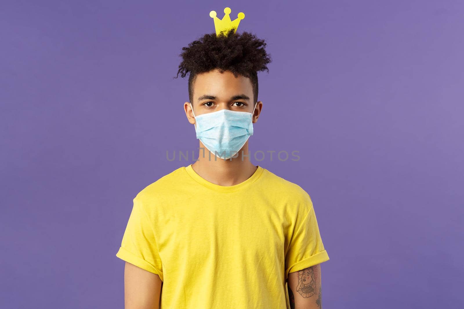 Portrait of funny hispanic guy in face mask, fool around, going crazy staying inside home during quarantine, wearing small crown and look camera, social-distancing, staying healthy covid19 pandemia by Benzoix
