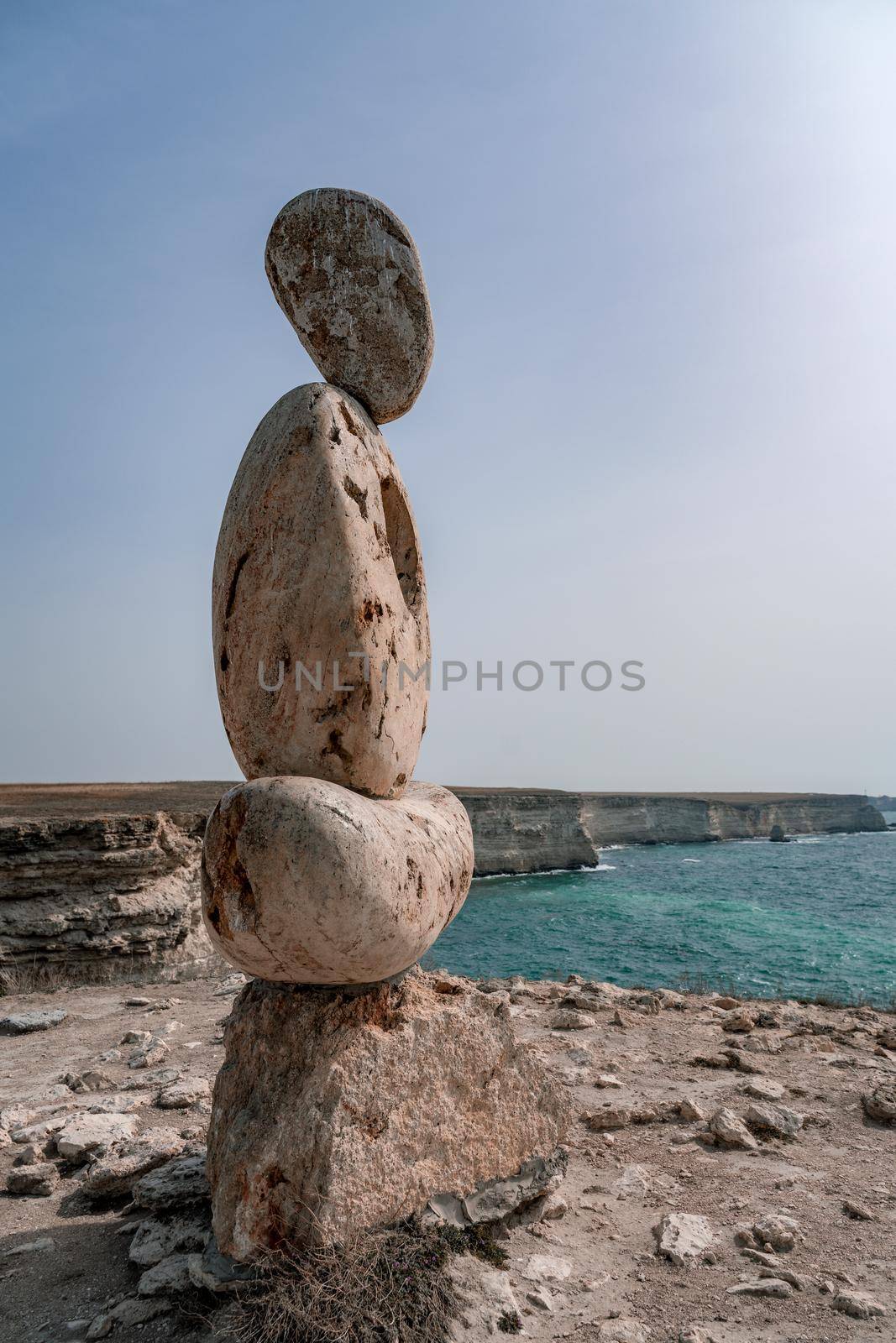 Sculpture symbol made of large pebbles against the blue sky by Matiunina