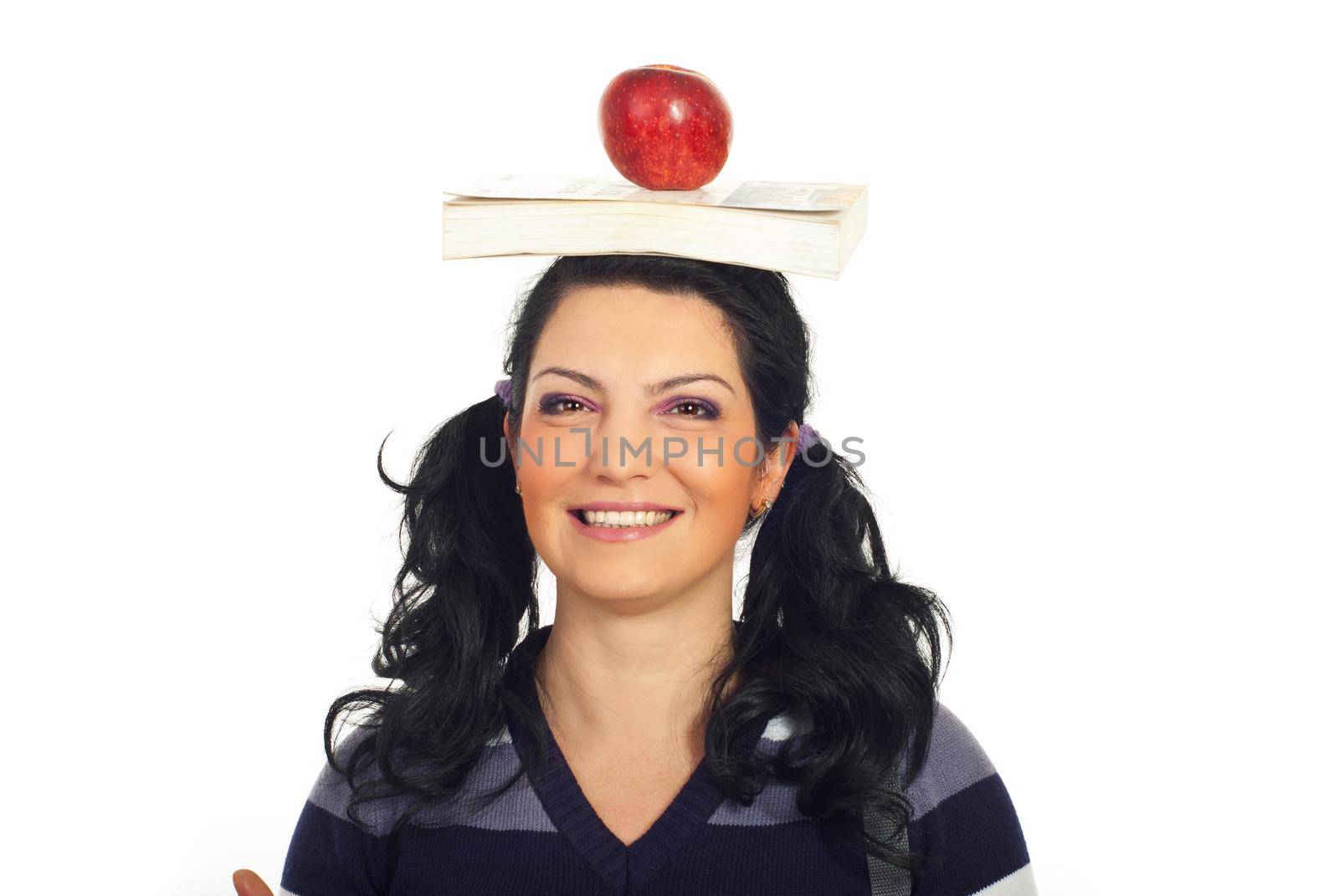 Portrait of smiling student female holding book and apple on her head isolated on white background