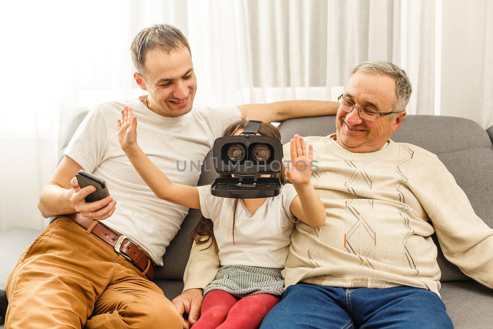 Granddaughter using virtual reality headset with her grandparents in living room at home