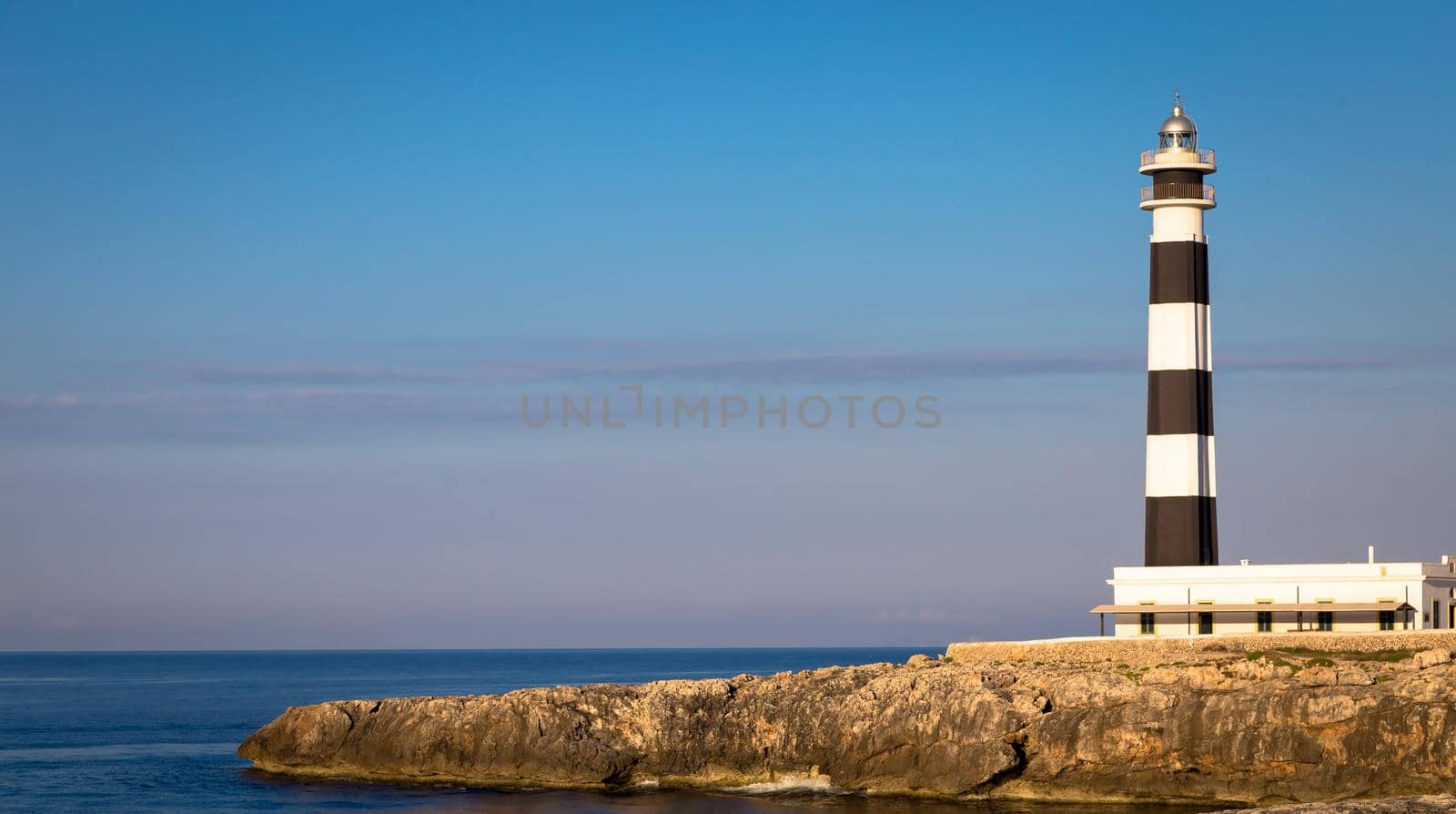 MINORCA ISLE - SPAIN - CIRCA AUGUST 2020: scenic Artrutx Lighthouse at sunset, famous landmark of the Isle