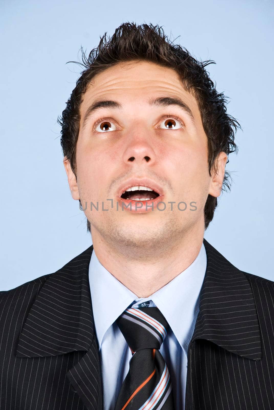 Portrait of amazed businessman with cool hairstyle looking up with mouth open and making big eyes