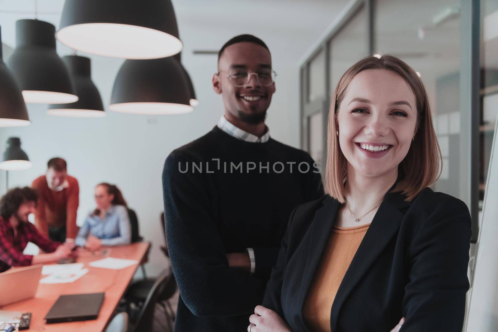 Portrait of happy businesswoman and businessman in modern office. Businessman and businesswoman smiling and looking at camera. Busy diverse team working in background. Leadership concept. Head shot. by dotshock