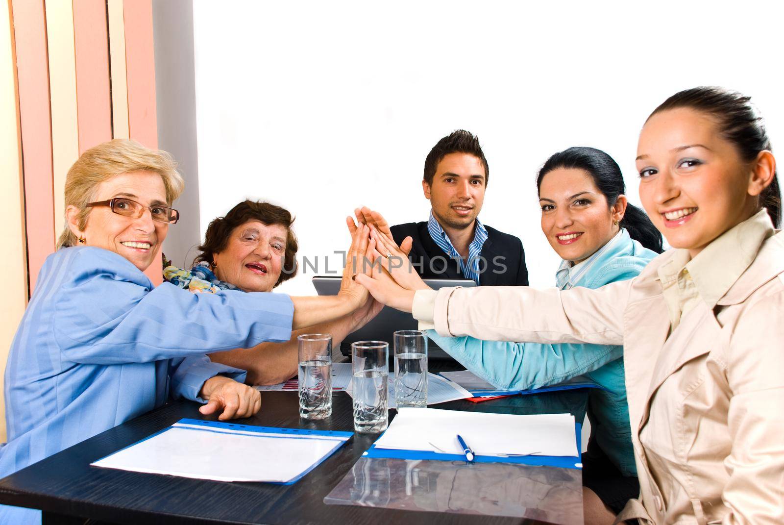 Group of business people giving high five and smiling  at  meeting or team spirit