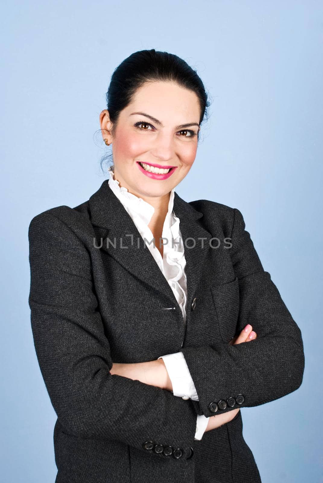 Happy  business woman 30s standing with arms folded  and smiling in front of blue background