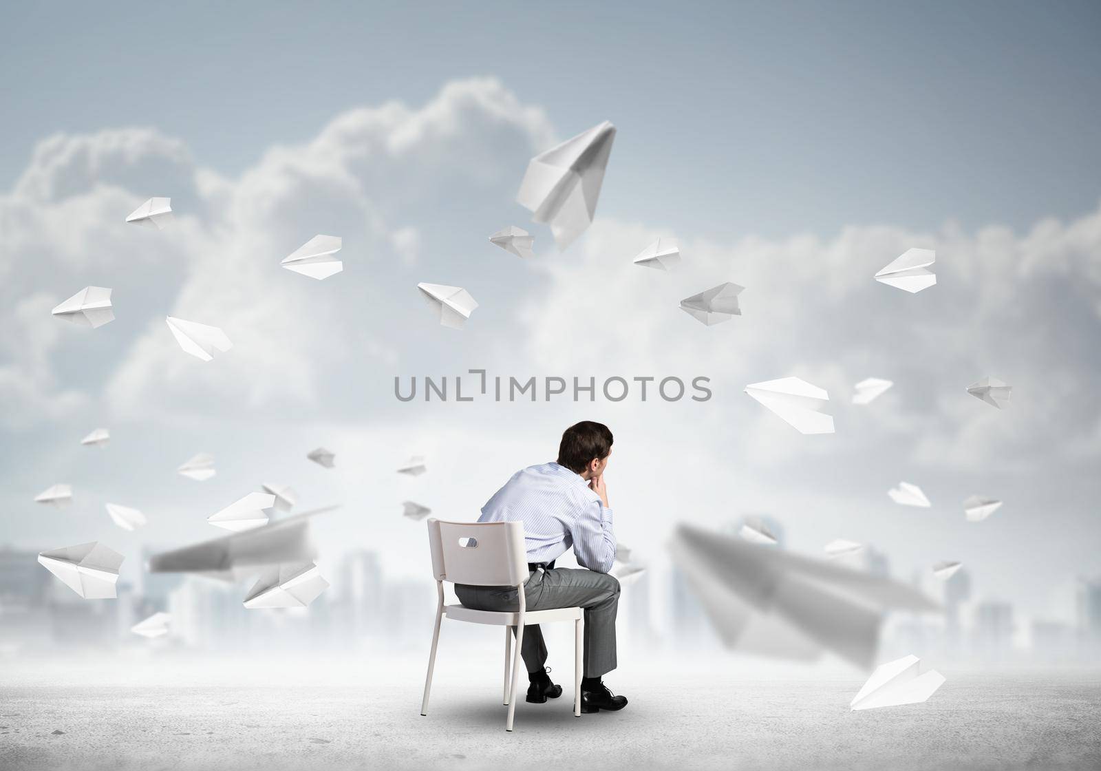 young businessman sits on an office chair, thoughtful and looking up