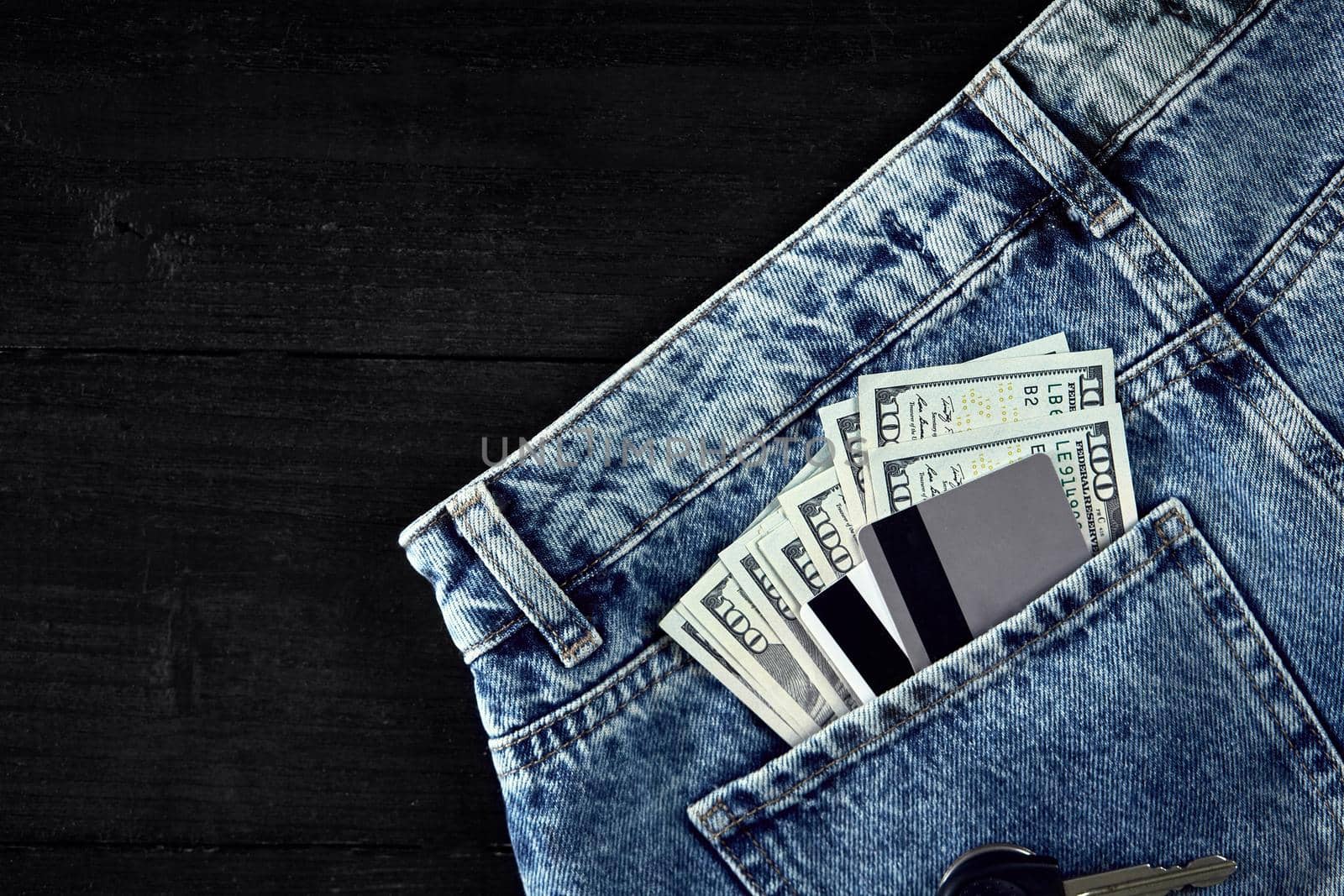 Cash and cards in your pocket jeans on black wooden background. Top view. Copy space. Still life. Flat lay