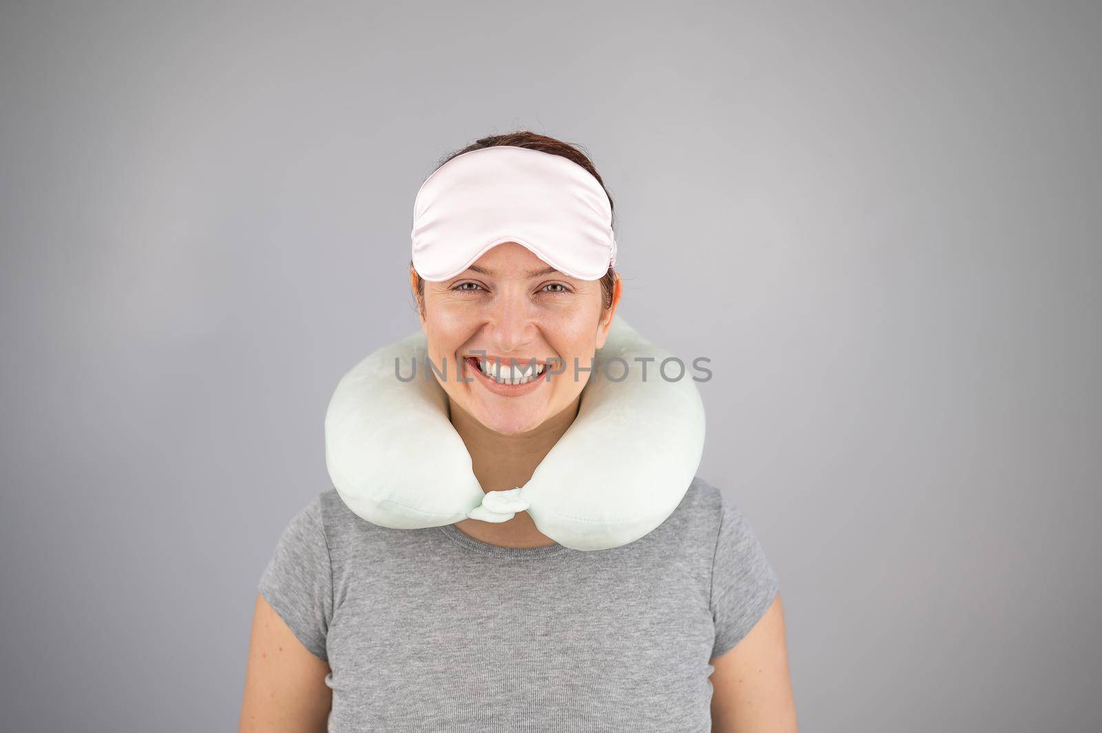 Smiling caucasian woman with travel pillow and sleeping mask isolated on white background. by mrwed54