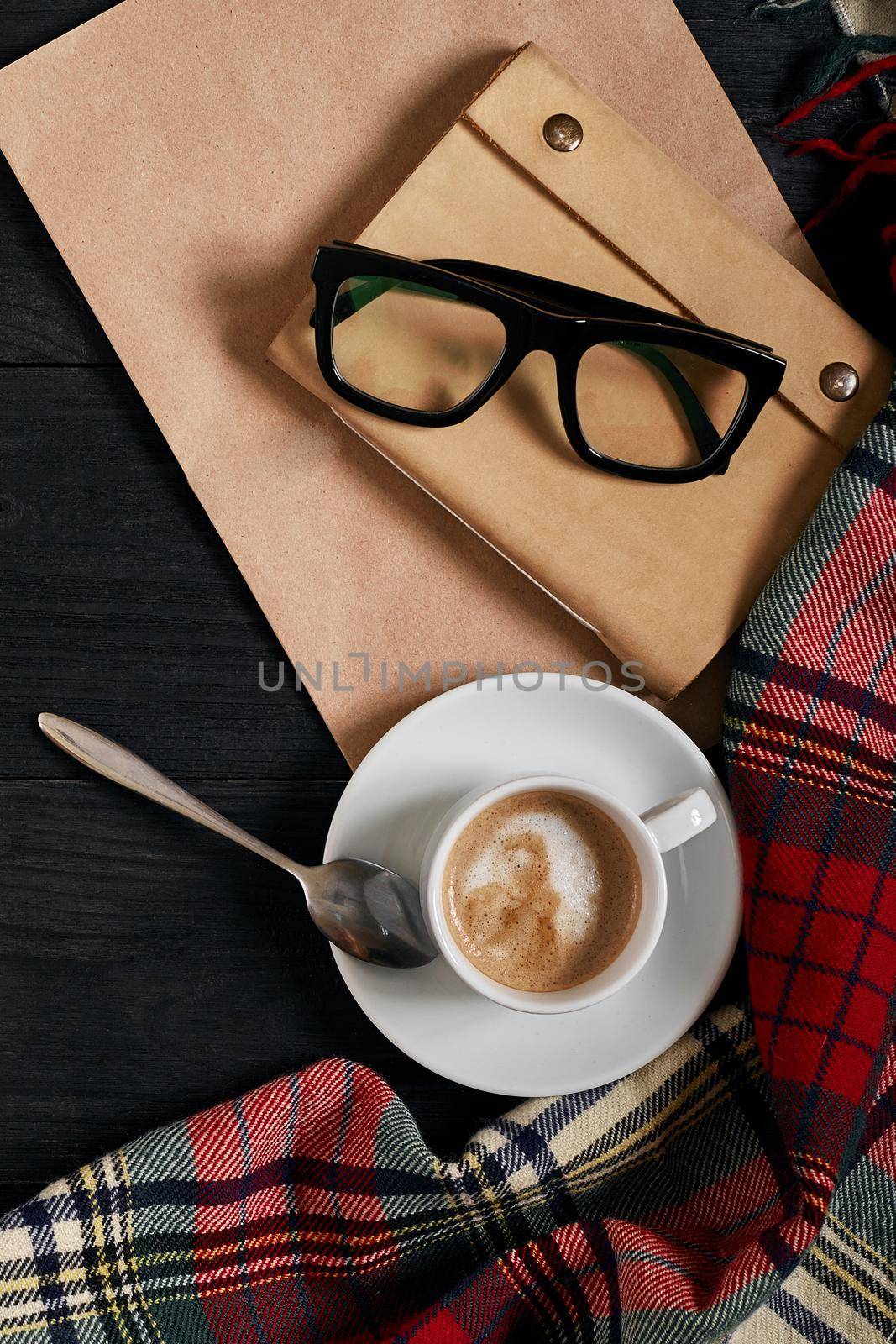 Above view of Smart phone with notebook and cup of latte coffee on black wooden background. Still life. Copy space. Flat lay. Top view