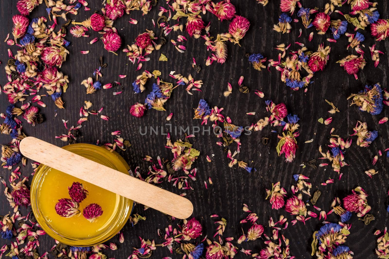 Organic honey in a small jar on a wooden background. Dried flowers. Still life. Top view. Copy space