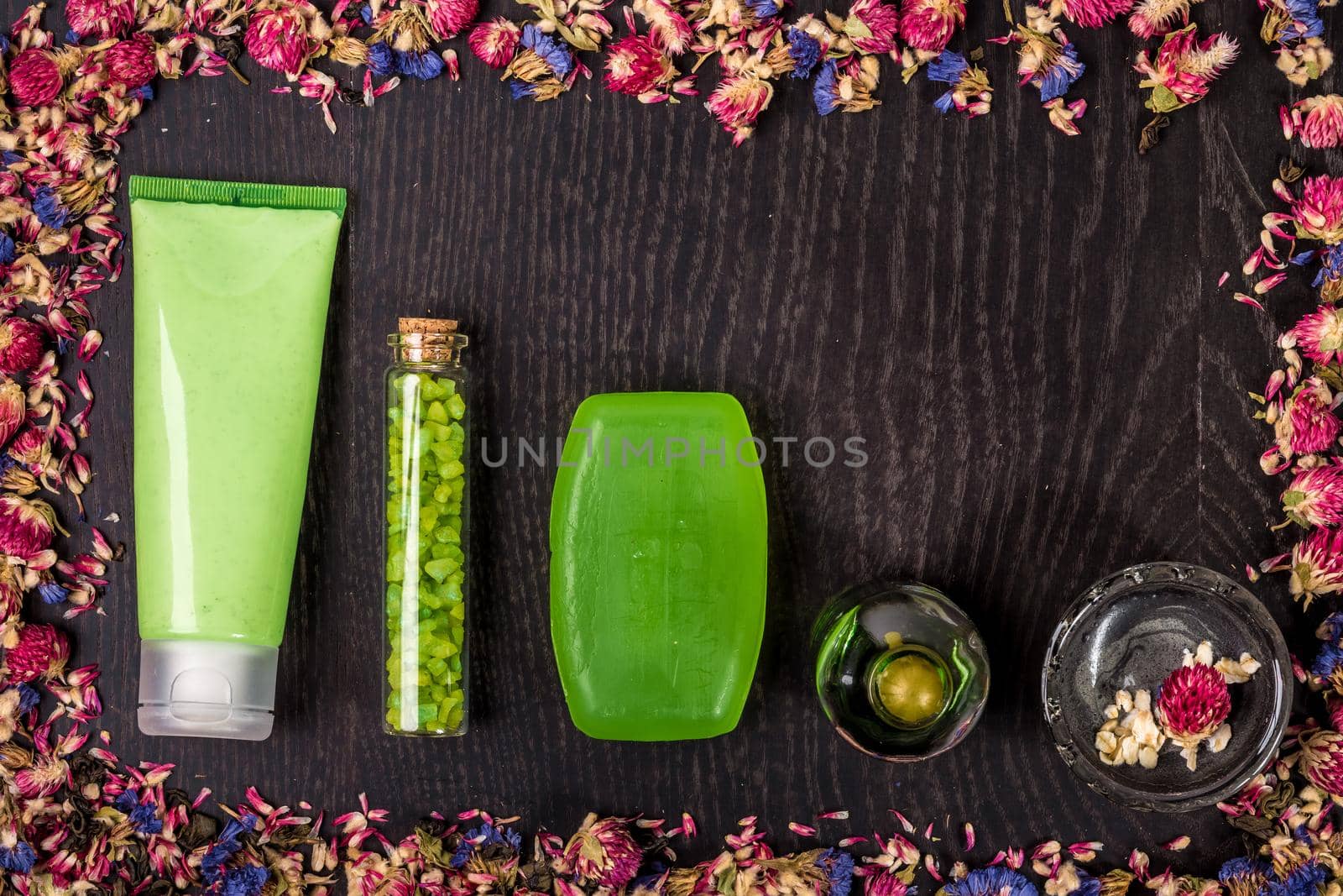 Cosmetic hygienic products with flowers on wooden background. Still life. Top view. Copy space