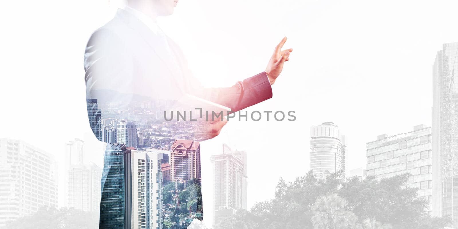 Businessman pointing on empty space on background modern cityscape. Standing entrepreneur in business suit and tie without face. Double exposure template. Blank screen ready for business message