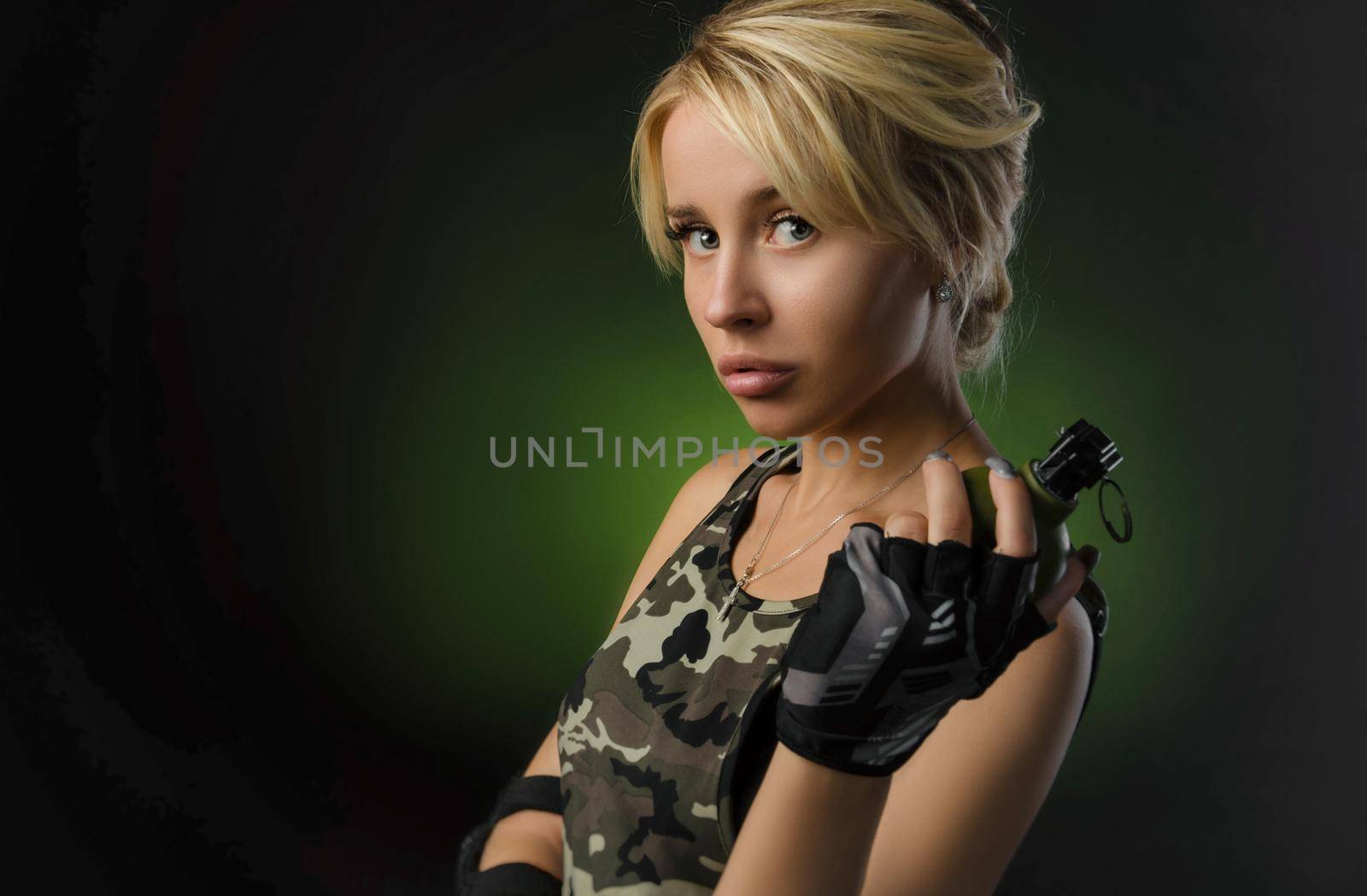 blonde girl in military clothes with a grenade in her hands on a dark background
