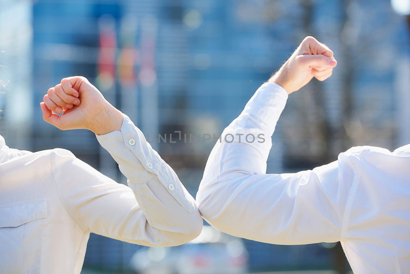 A close-up photo of elbow bumping. Elbow greeting to avoid the spread of coronavirus (COVID-19). Colleagues meet in the street. Instead of greeting with a hug or handshake, they bump elbows.