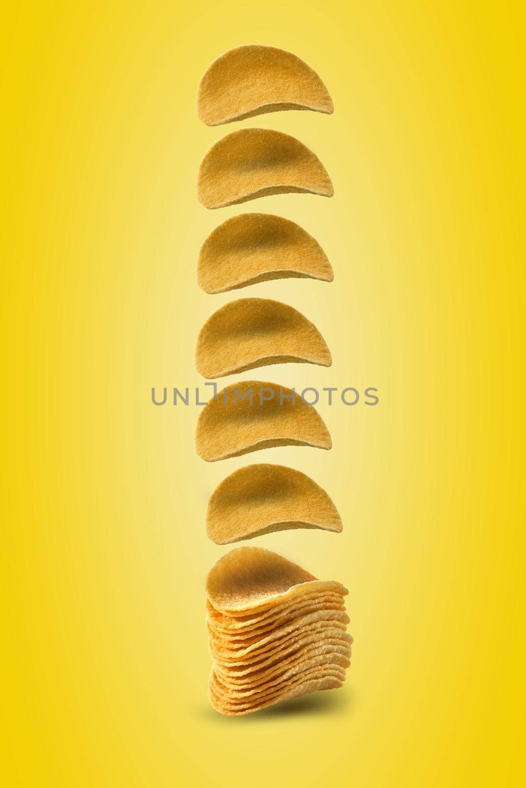 Gourmet potato crisps falling down against a yellow background with copy space for your text or images. Crispy, palatable chips. Shadow. Advertising concept. Close-up shot.