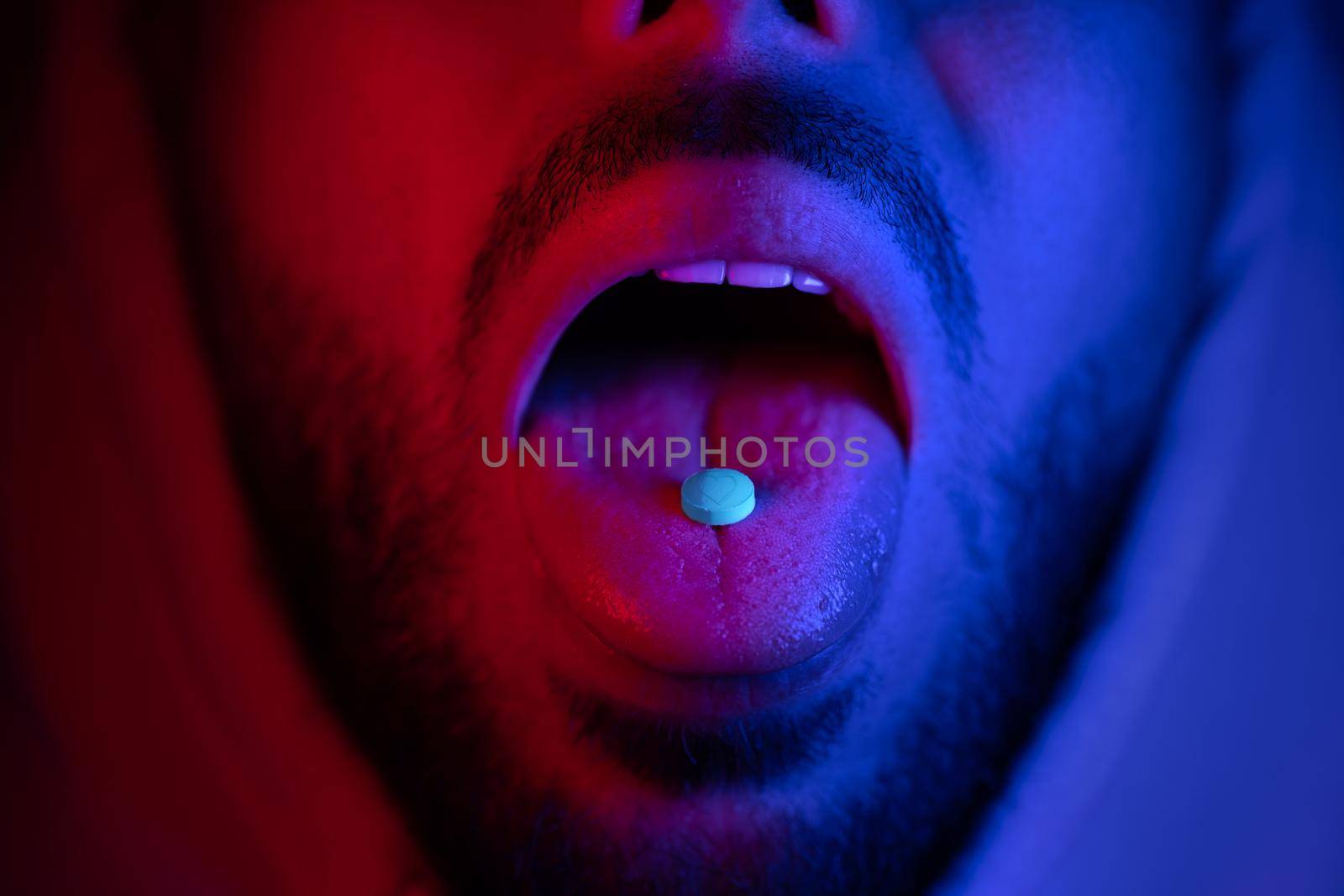 Close up of man mouth swallowing ecstasy drugs. Man taking MDMA ecstasy pill. by DariaKulkova