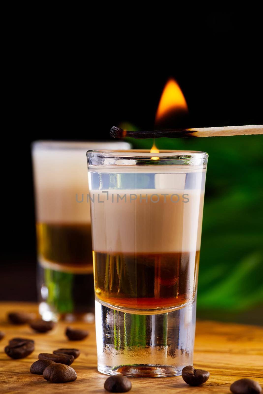 Shots of flaming B-52 cocktail placed on a bar counter. B-52 shot composed of three liqueurs by PhotoTime