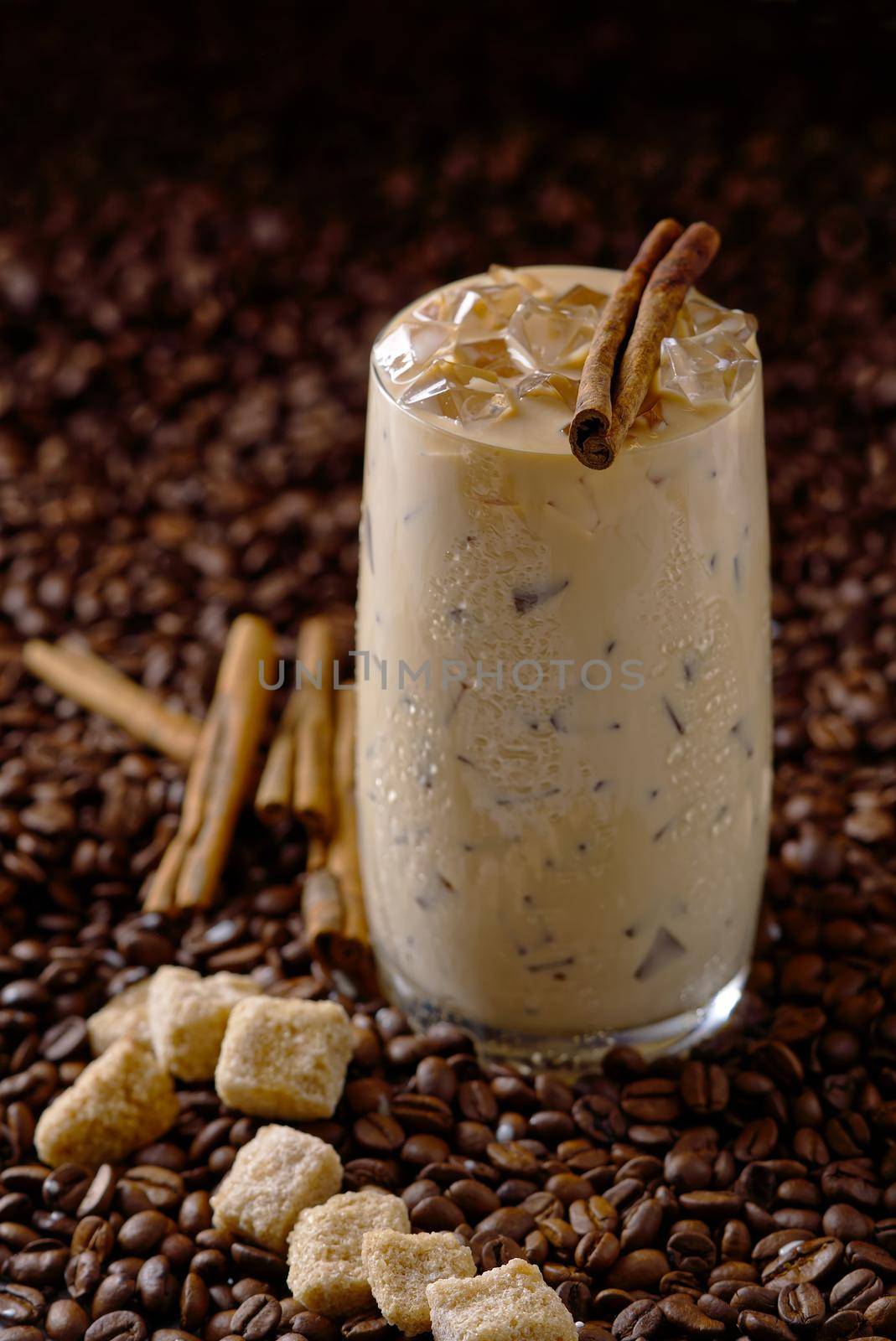 Iced latte coffee. Cup of Iced latte coffee, milk tea on dark coffee seeds background. Could Coffee with cardamom and cinnamon.