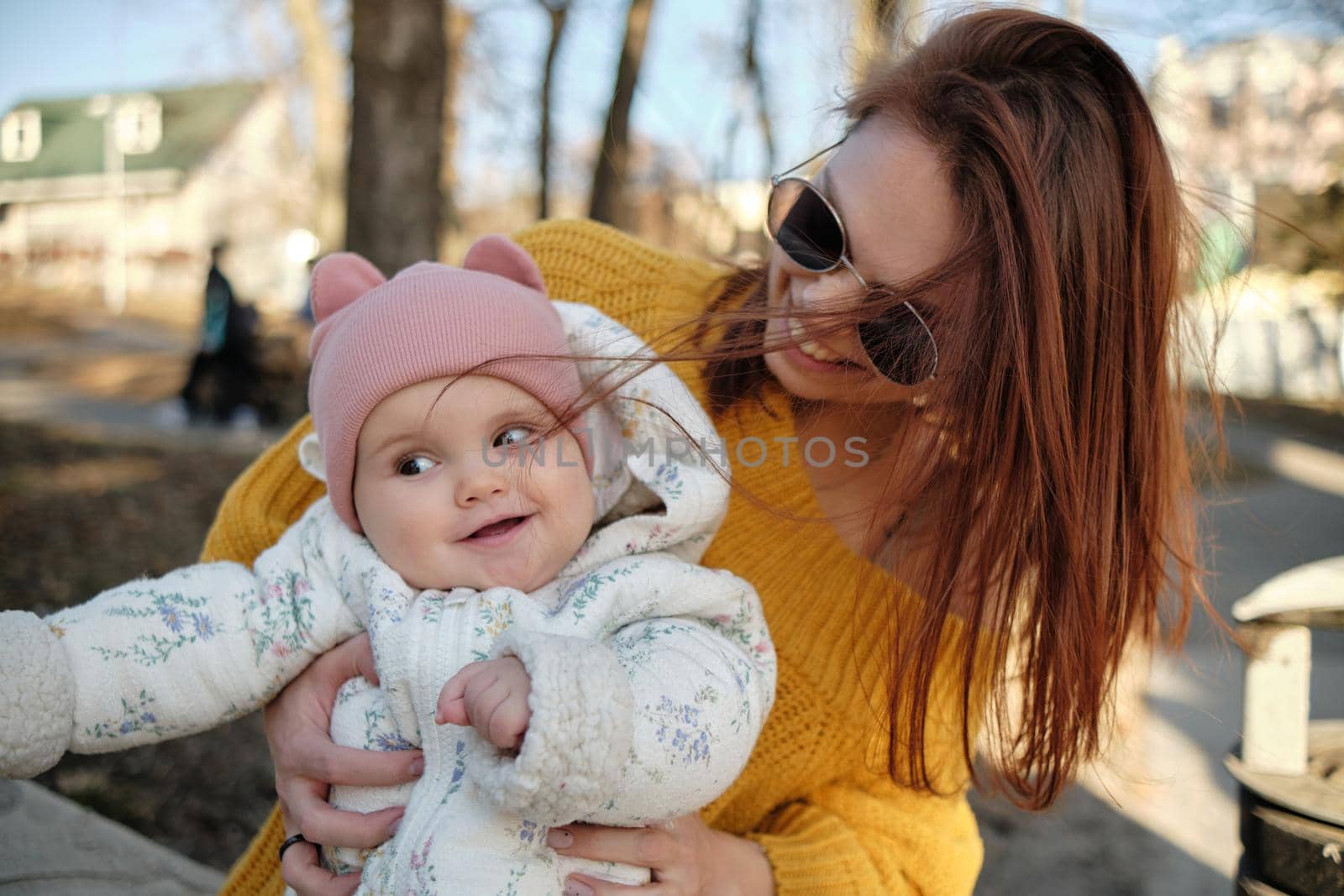 Mother holding baby smiling to camera. Real life authentic casual mom looking to camera holding infant