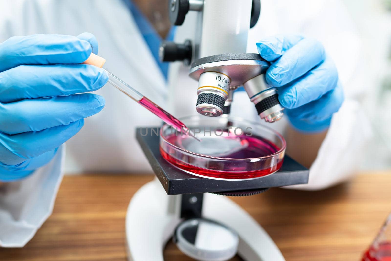 Asian scientist biochemist or microbiologist working research with a microscope in laboratory. For protect outbreak Coronavirus Covid19, bacteria and germs.