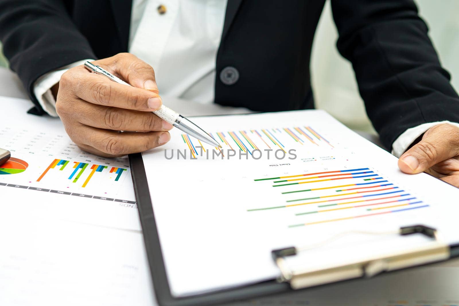 Asian accountant working and analyzing financial reports project accounting with chart graph and calculator in modern office,finance and business concept. by pamai