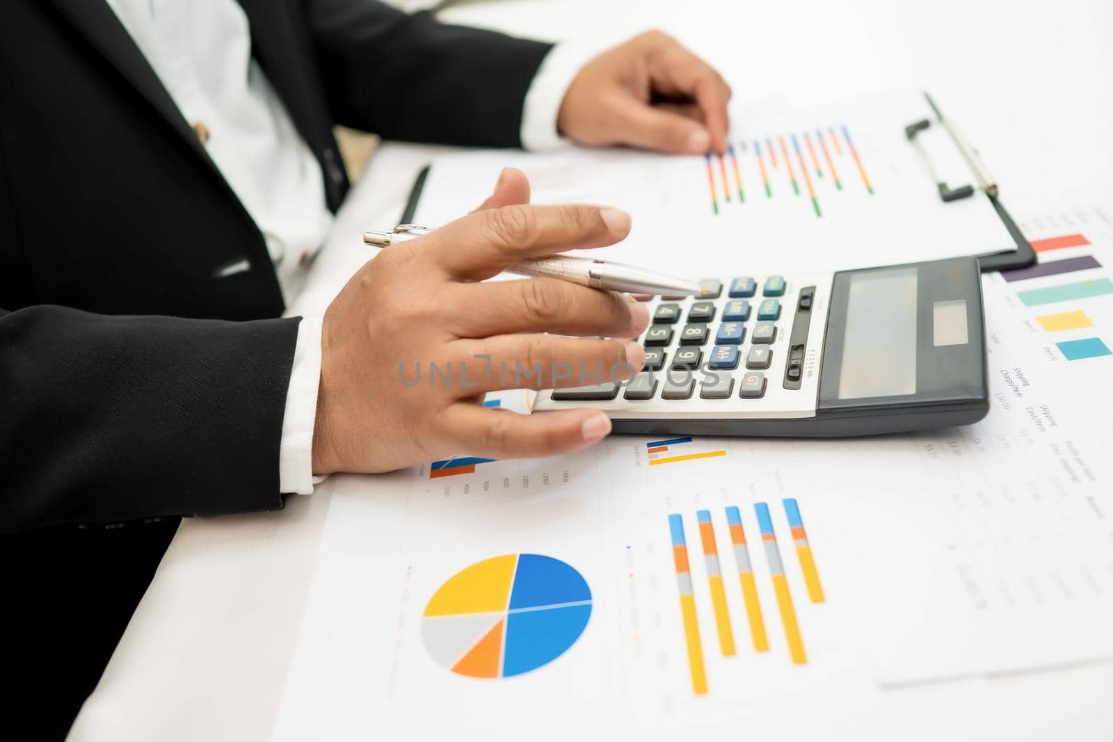 Asian accountant working and analyzing financial reports project accounting with chart graph and calculator in modern office,finance and business concept.