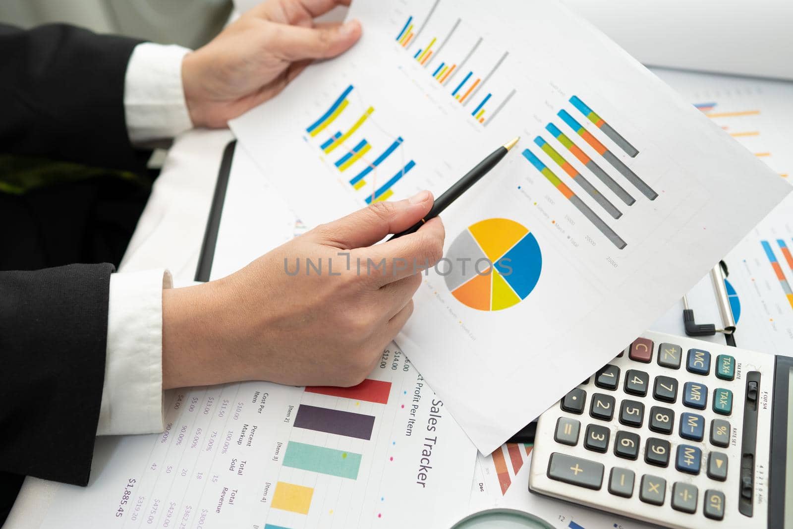 Asian accountant working and analyzing financial reports project accounting with chart graph and calculator in modern office,finance and business concept. by pamai