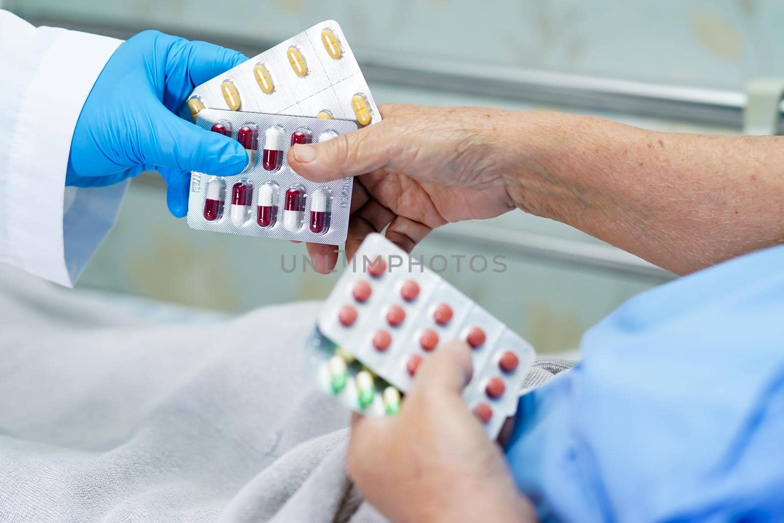 Asian doctor holding antibiotics capsule pills in blister packaging with senior lady patient for treatment infection patient in hospital, Pharmacy drugstore concept.